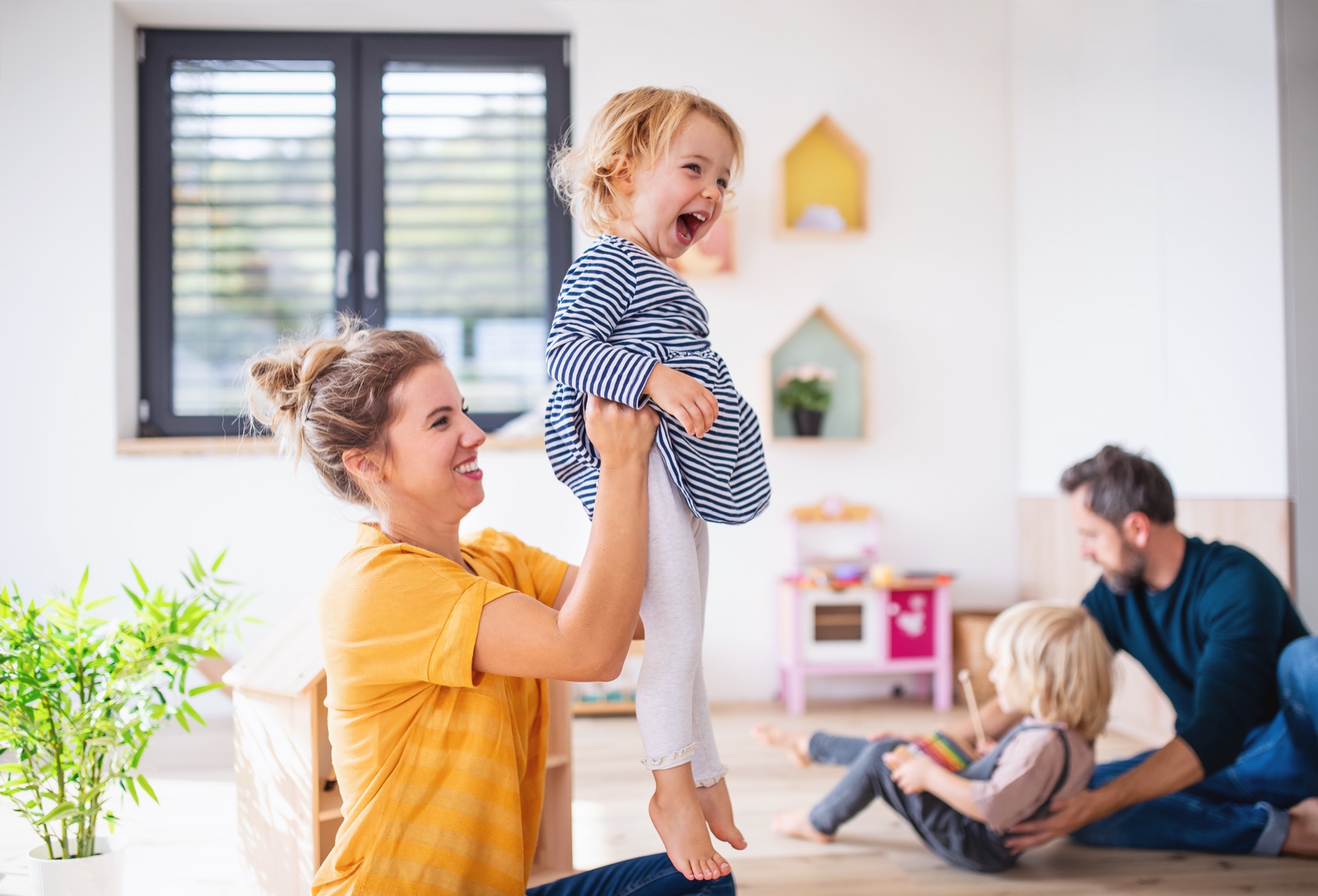 Jeune famille avec deux petits enfants à l'intérieur dans la chambre, s'amusant
